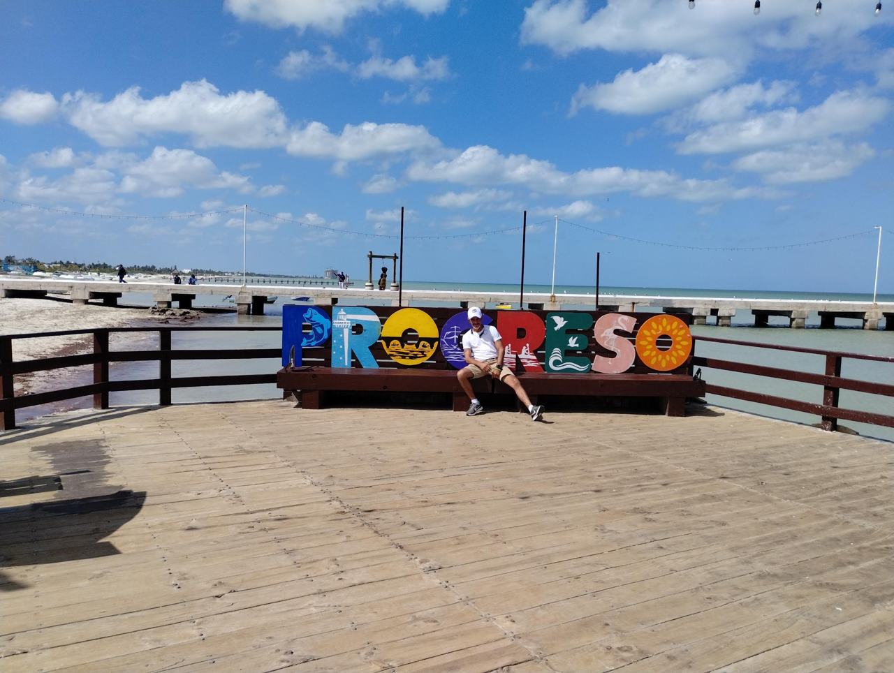 Viajeros en las letras de Progreso frente al muelle
