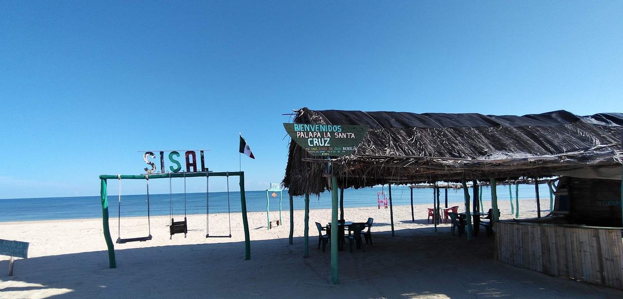 Columpios y letras de Sisal frente al mar, junto a una palapa