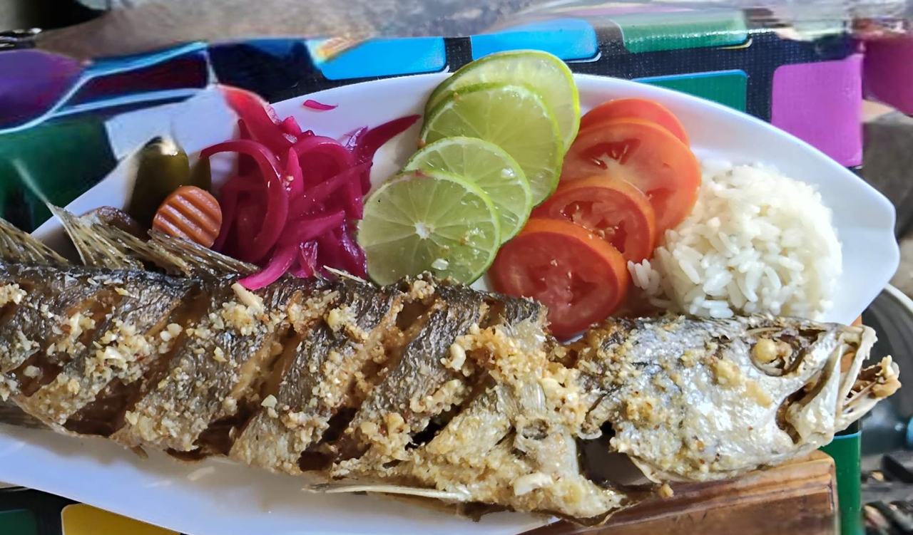 Pescado frito con limón, cebolla morada y arroz en Sisal